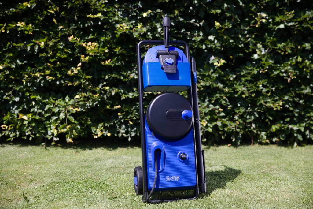 Blue pressure washer on grass, ready for outdoor cleaning tasks.