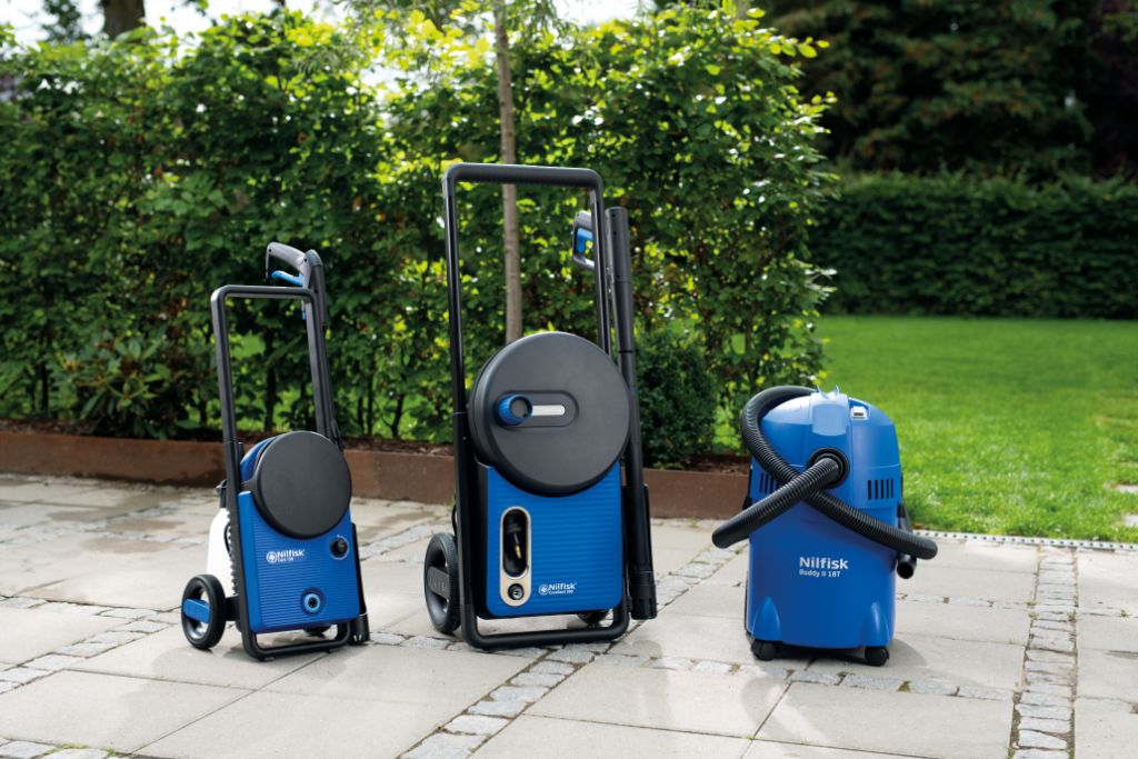 Three blue Nilfisk cleaning machines—pressure washers and wet/dry vacuum—lined up on a patio, ready for outdoor use.
