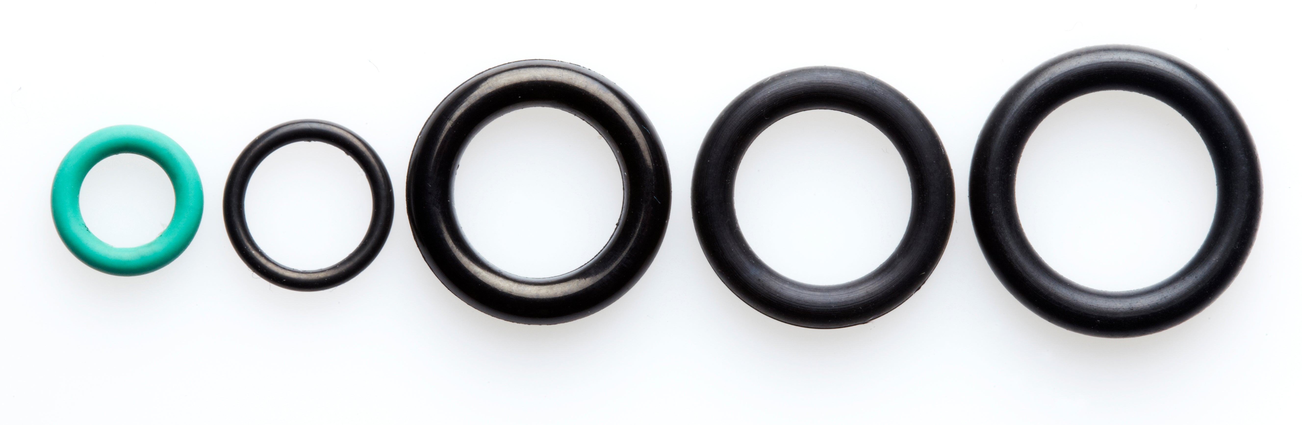 Five O-rings of varying sizes and colors, including one green, arranged in a row on a white background, showcasing replacement parts for high-pressure cleaners.