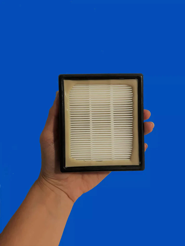 Hand holding a clean HEPA filter against a vibrant blue background, showcasing its fine pleated design for air purification.