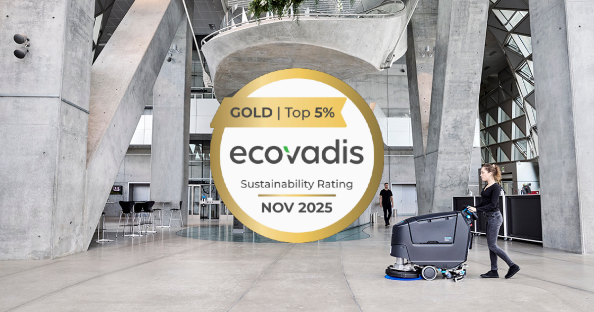 Woman operating Nilfisk floor cleaner in modern concrete space, with EcoVadis Gold Sustainability Rating badge prominently displayed.