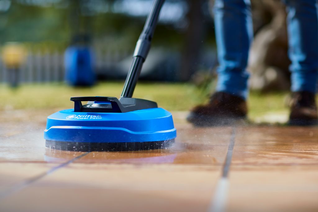 Blue power patio cleaner by Nilfisk showing a floor cleaning head in action.