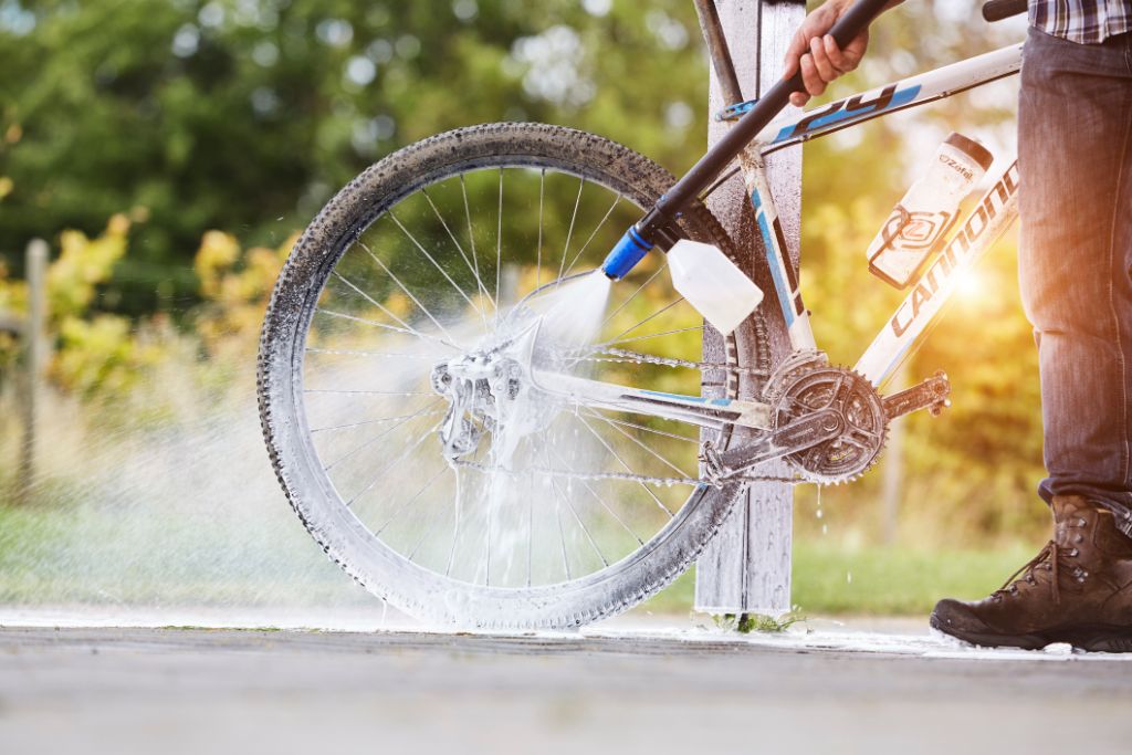 High-pressure cleaner cleaning agent for bikes and motorcycles, by ES, being used to clean a bicycle wheel outdoors.