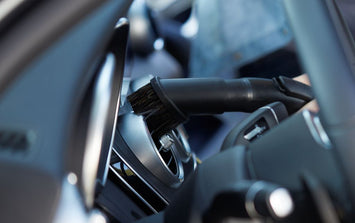 Car wet/dry vacuum by ES Buddy with brush attachment cleaning the air conditioning vent.